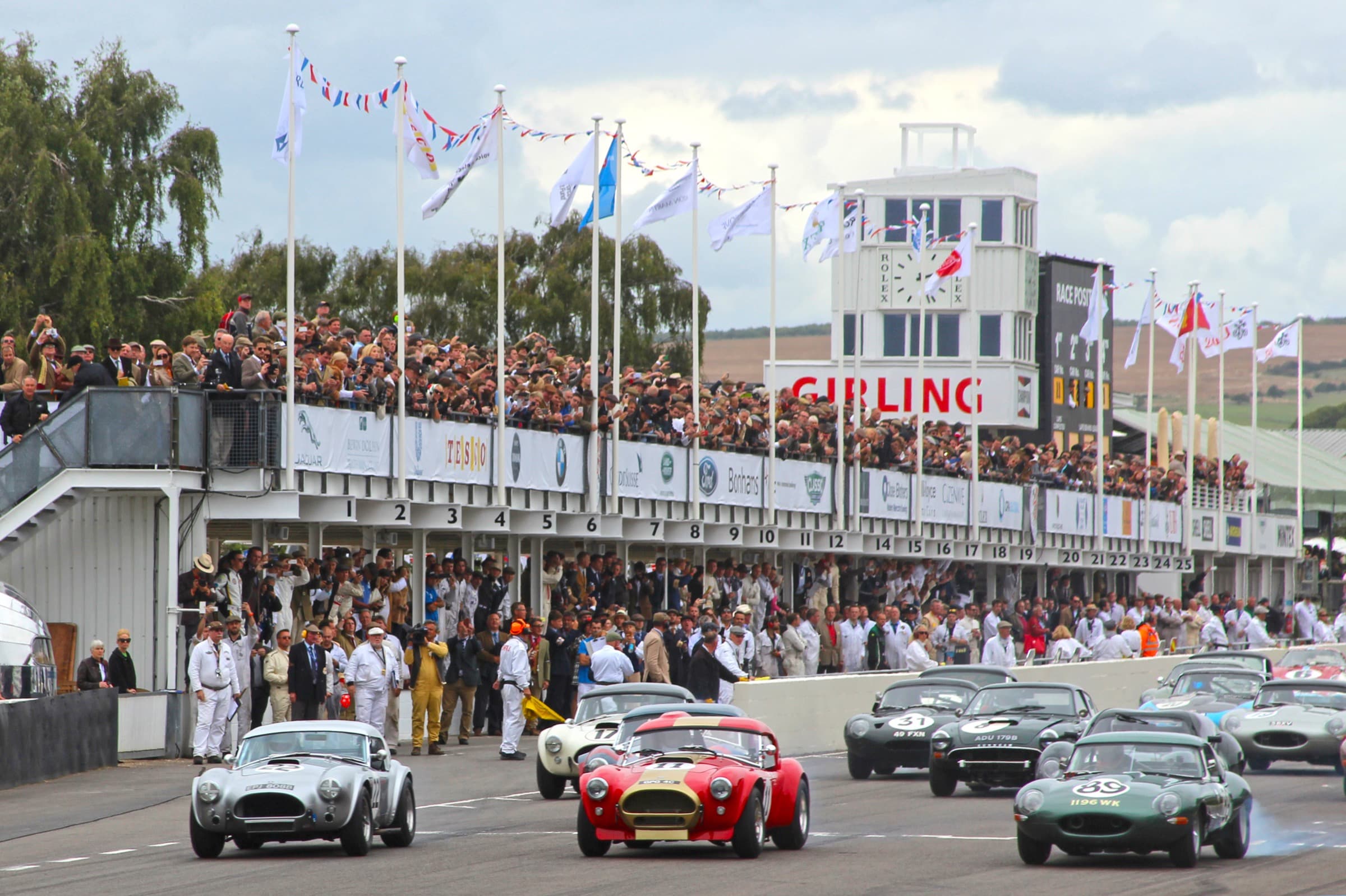A field of vintage British sports cars at the start of a race, Goodwood Revival